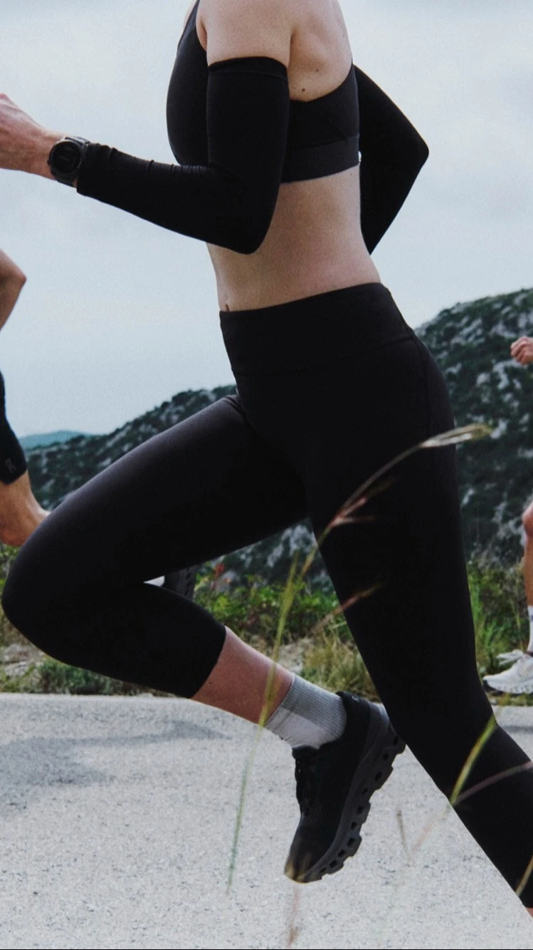 Three runners in On apparel running on a mountain road.