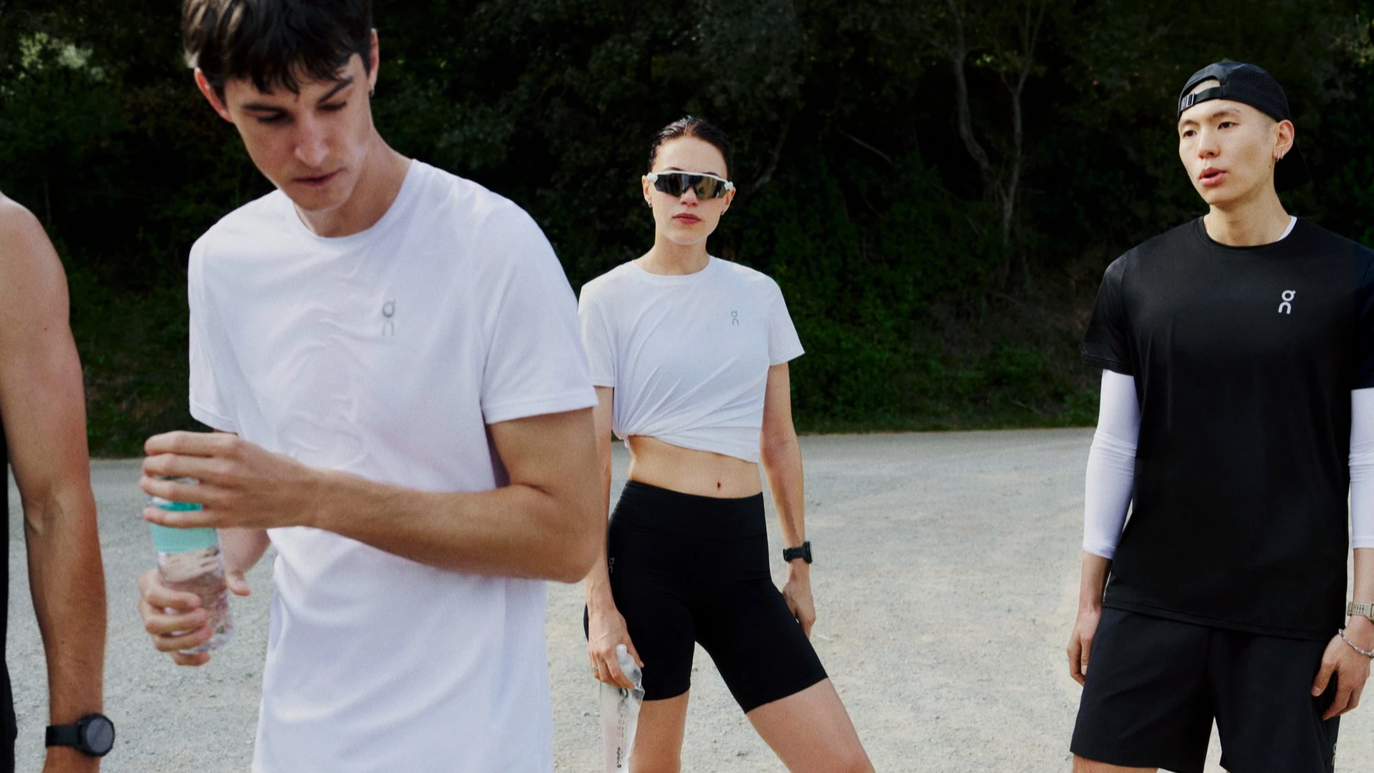 A group of runners standing at rest, water bottles in hand.