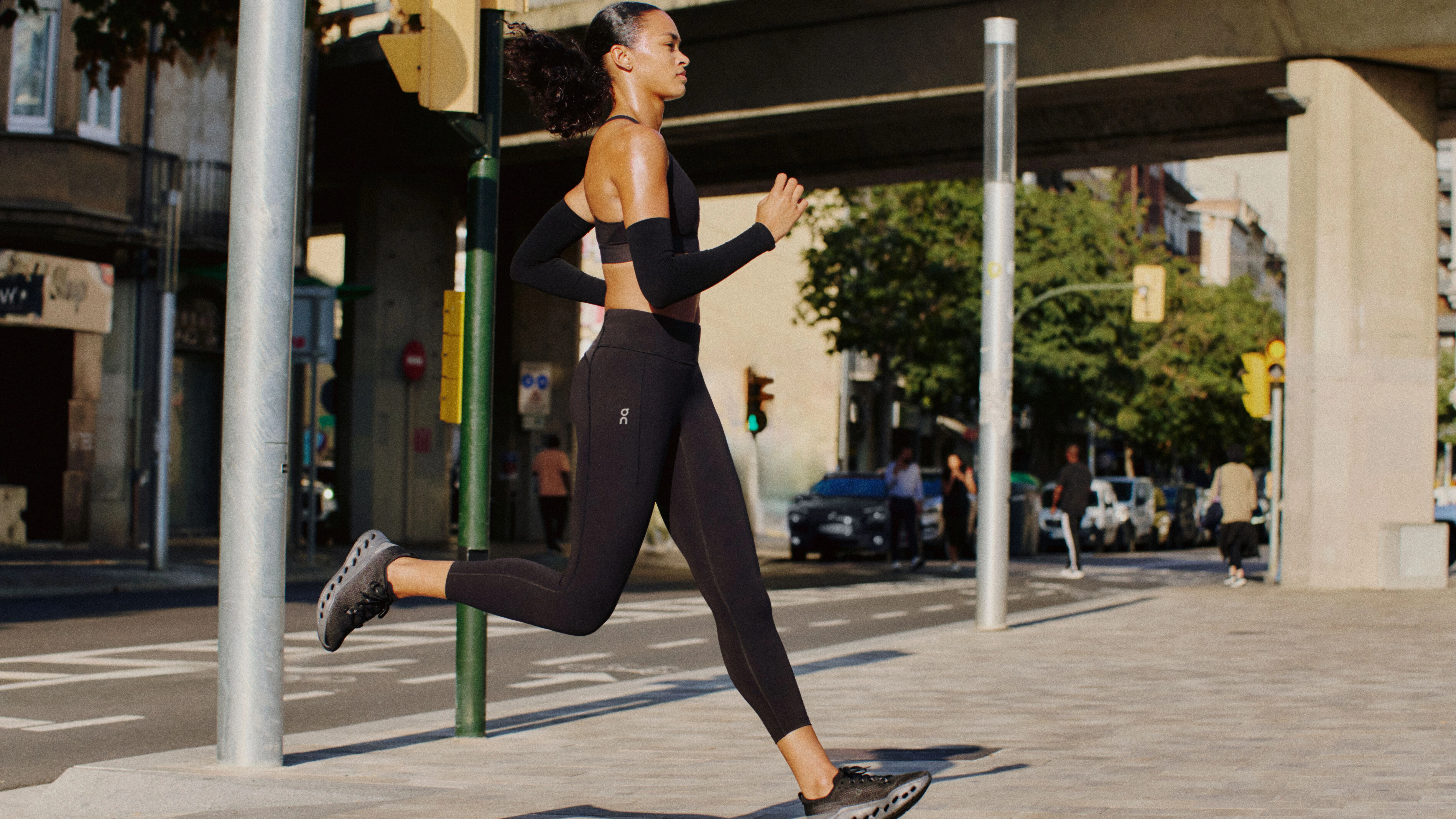 Runneuse en pleine foulée portant un legging et une brassière de sport On en milieu urbain.