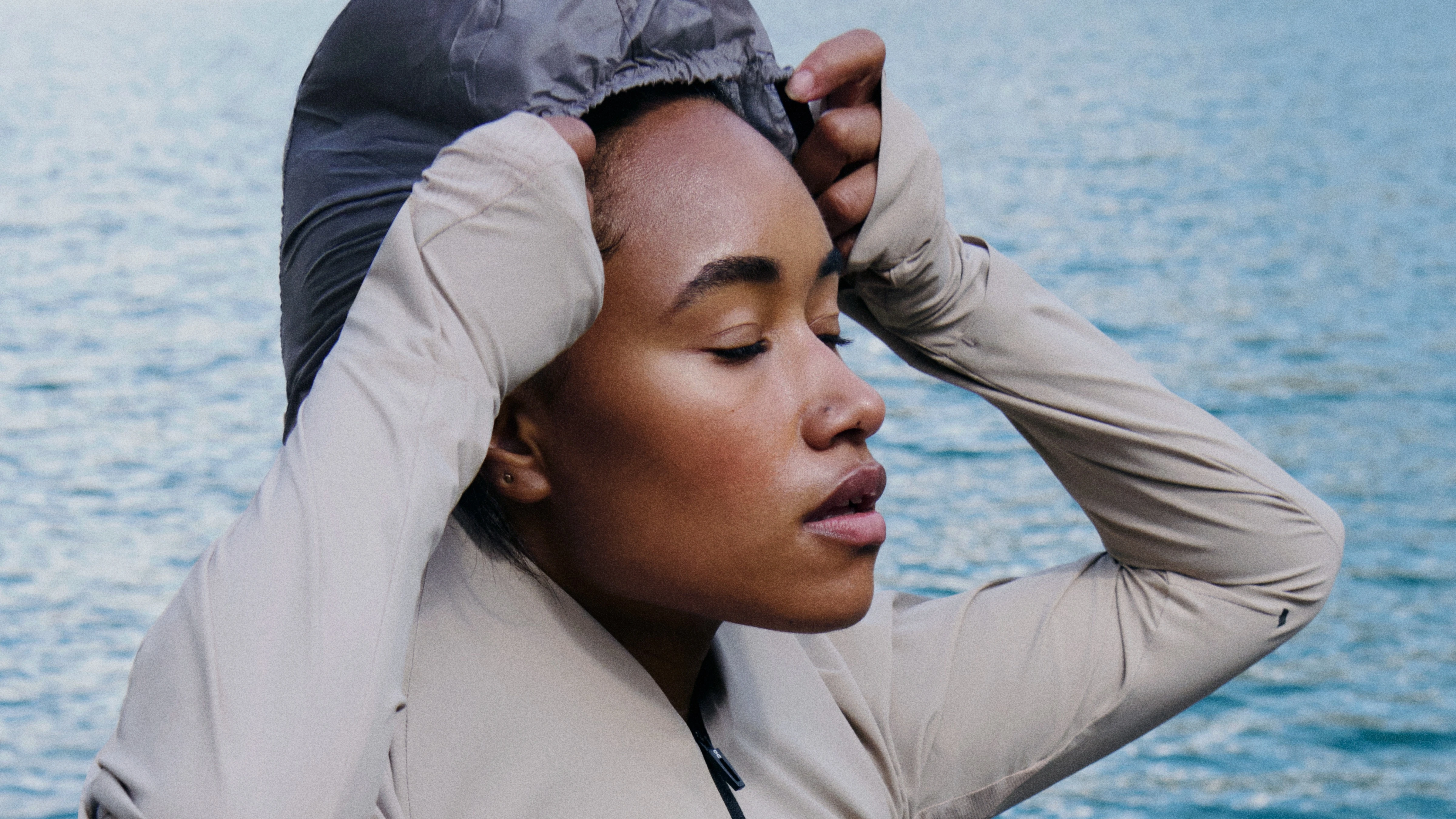 Runner junto al agua con los ojos cerrados y poniéndose la capucha.