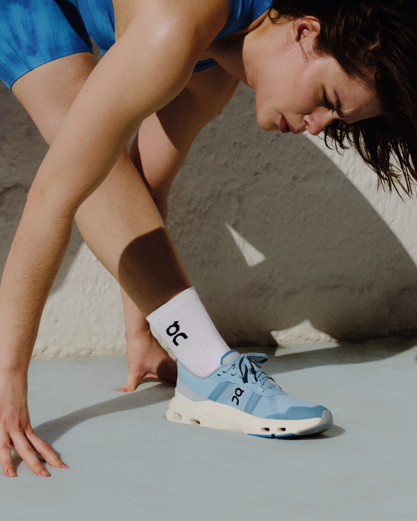 Woman stretching before a run while wearing cushioned running shoes.