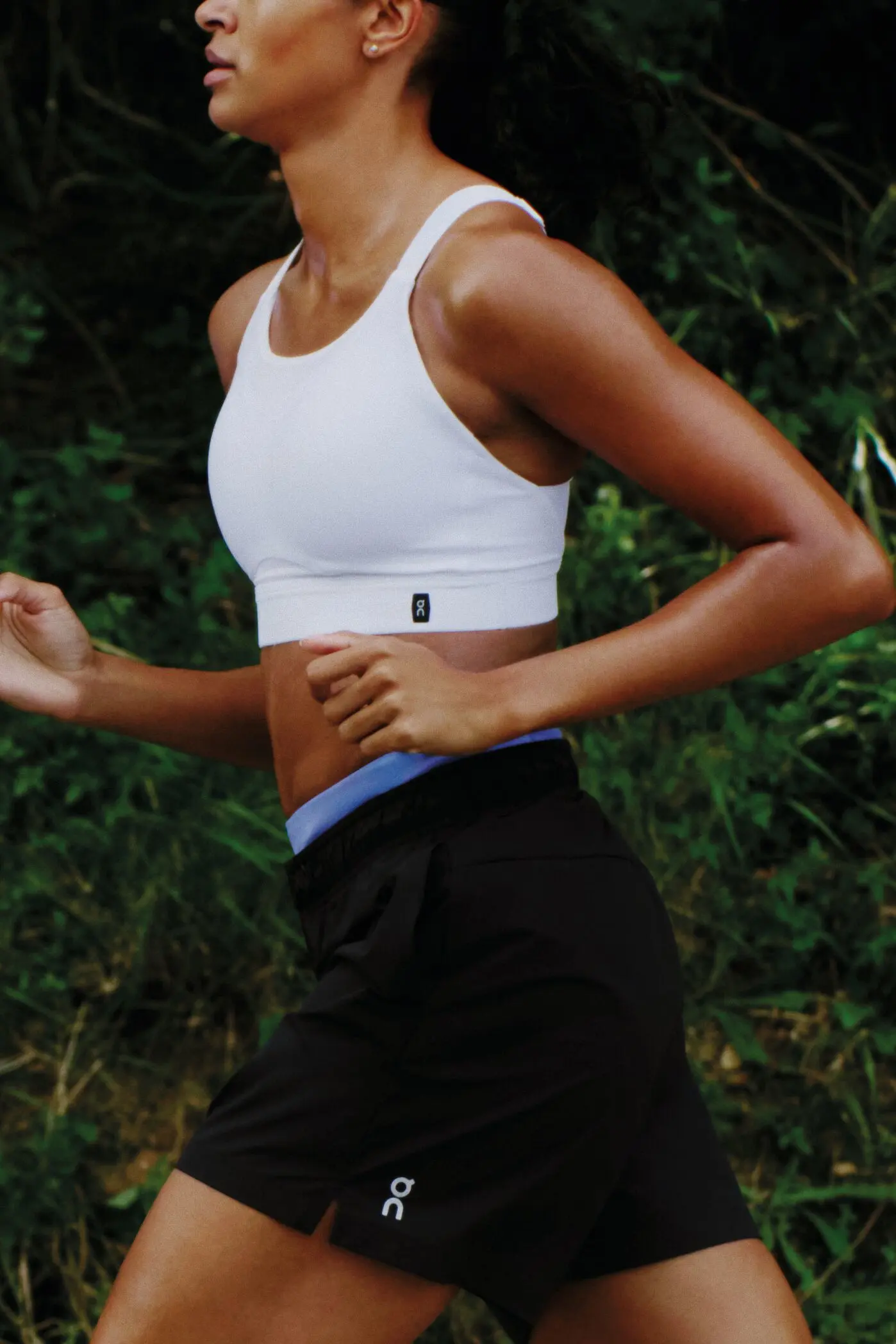 A runner pictures from the knees up, in an On sports bra and shorts.