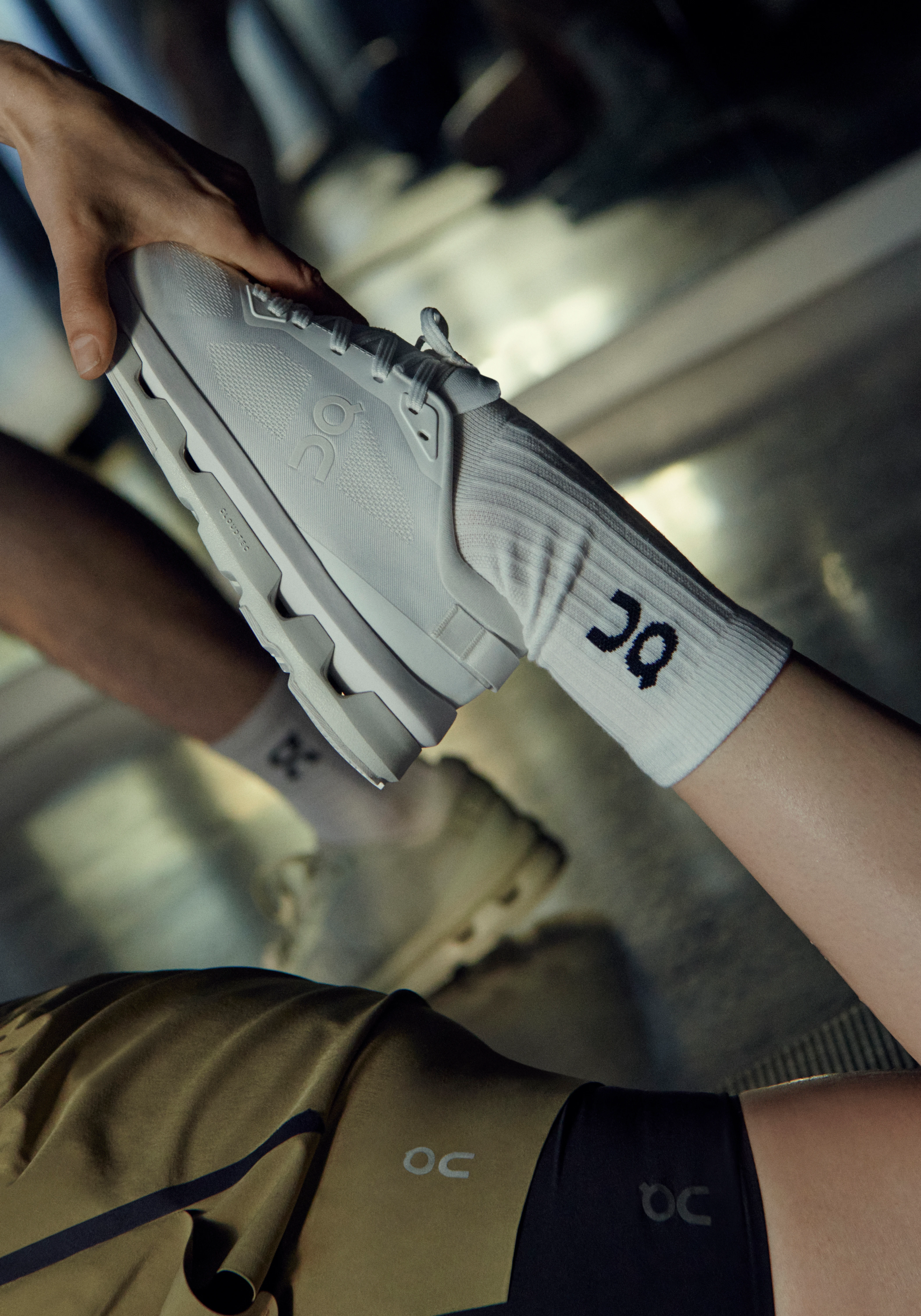 A woman stretches in a gym while wearing On shoes.