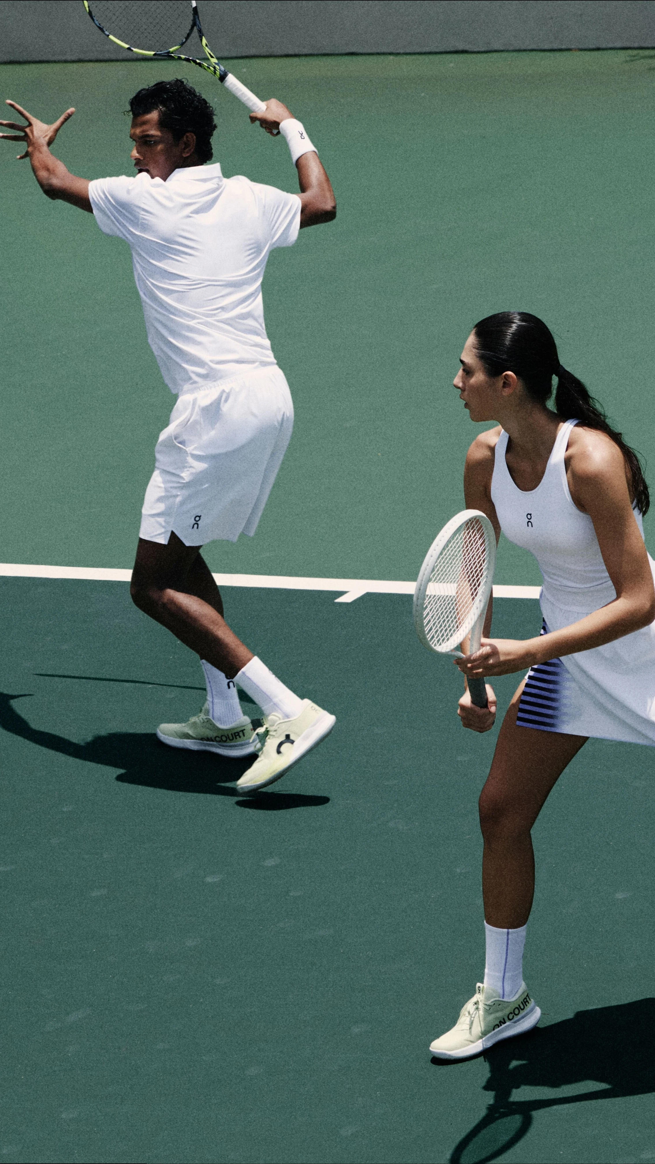 Tennisspieler*innen beim Ballwechsel in weissen Tennis-Outfits von On.