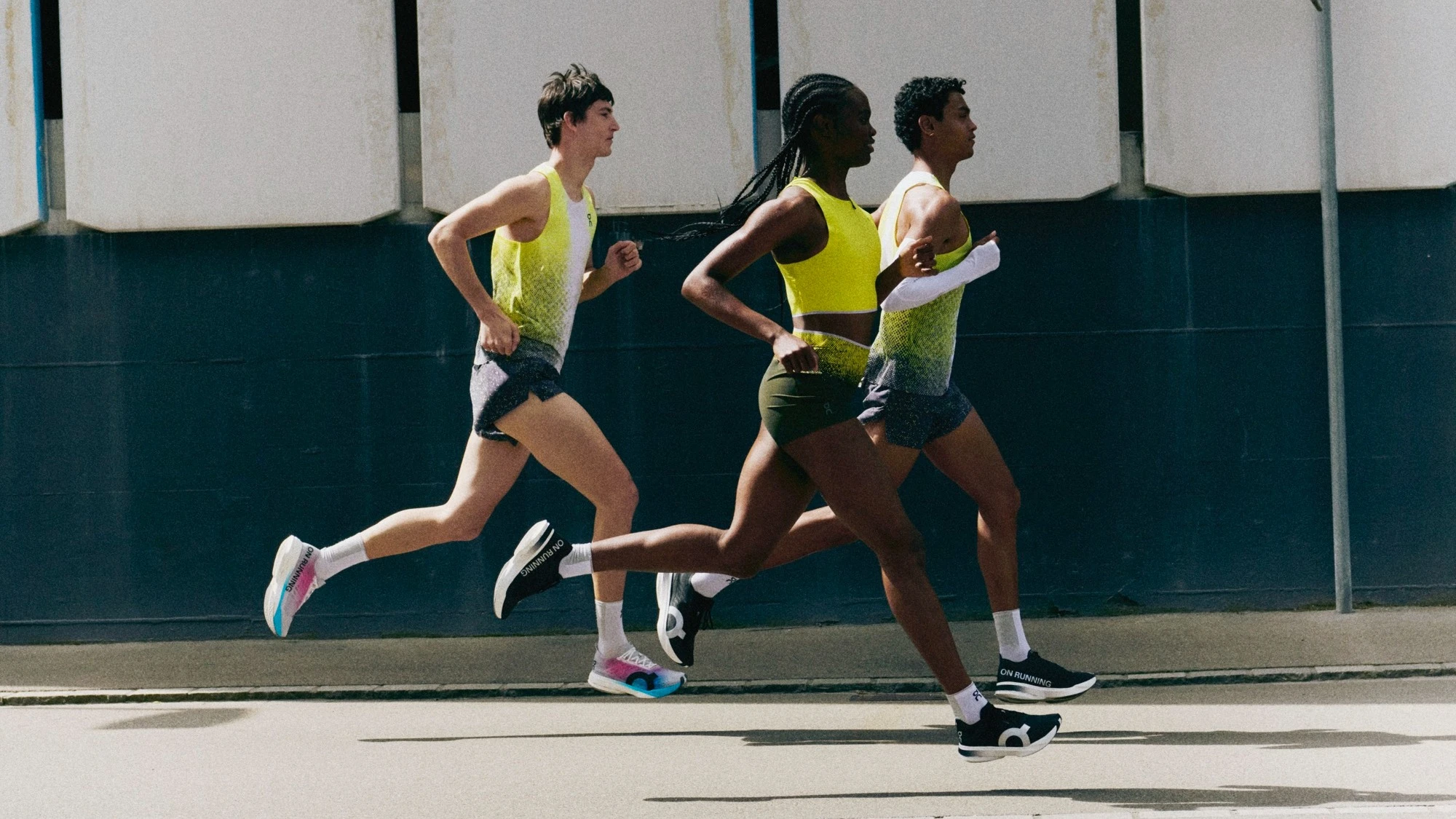 Three people mid-stride running on the road.