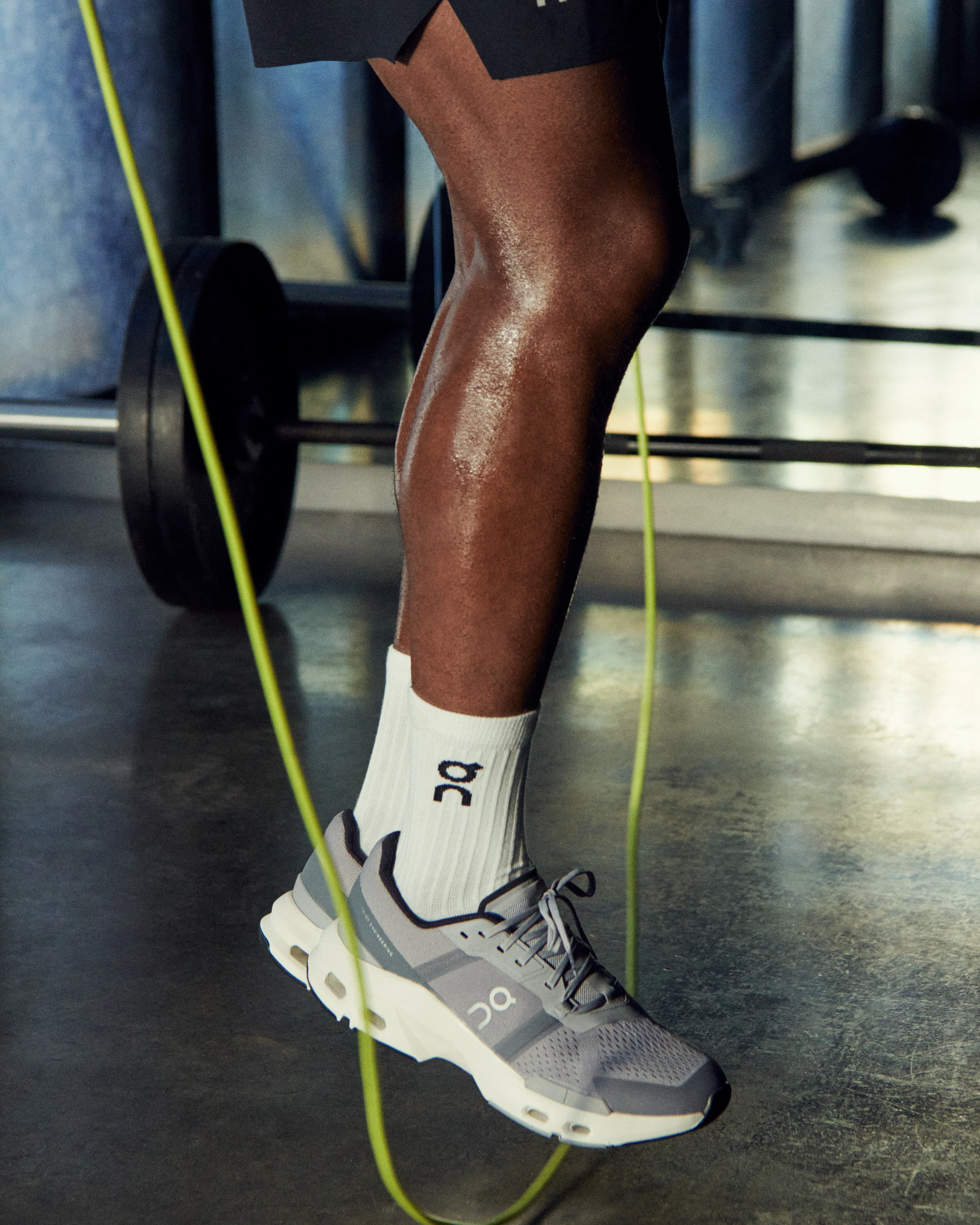 Pictured from the hip down, a person jumping rope wearing On shorts, socks and running shoes. 