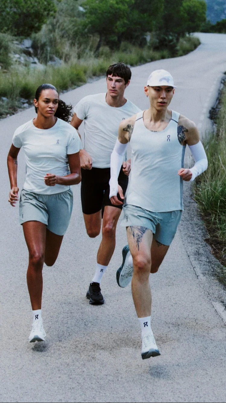 Three runners in On gear on a paved mountain road.