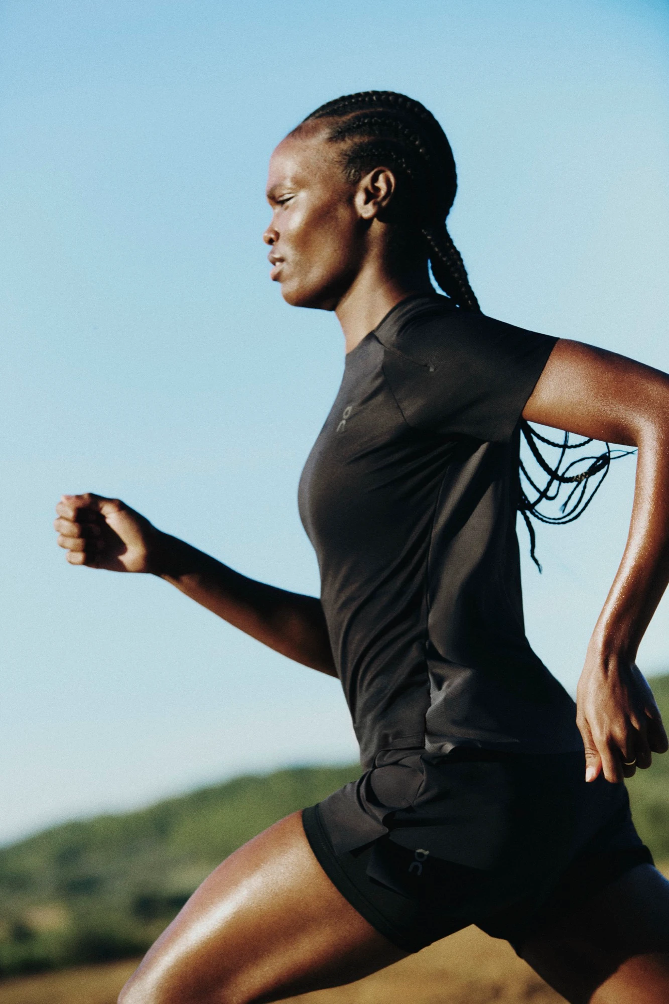 A runner in all black attire is shown jogging against a blue sky.