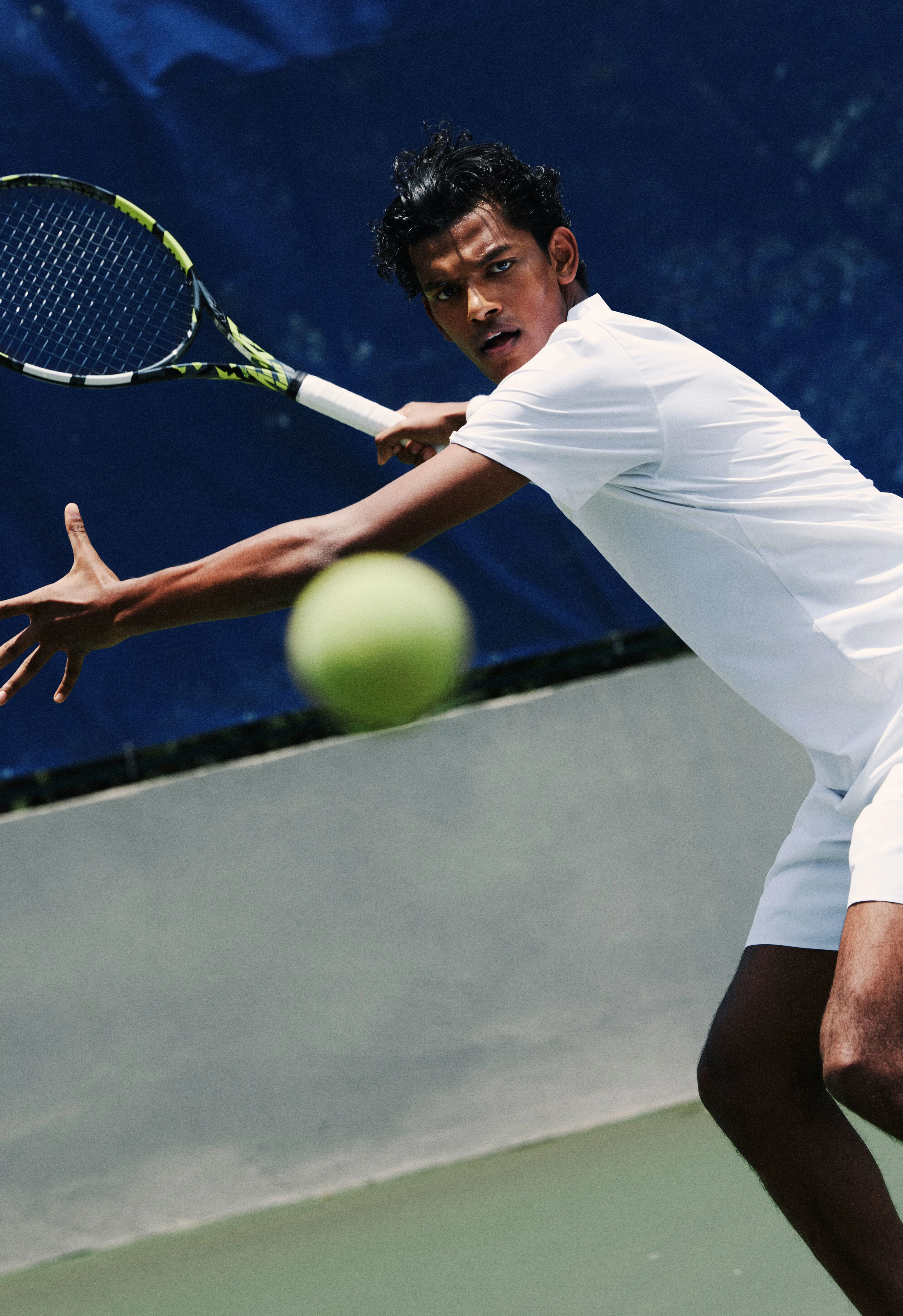 Ein*e Tennisspieler*in bereitet sich auf den Schlag vor, während der Ball im Vordergrund zu sehen ist.