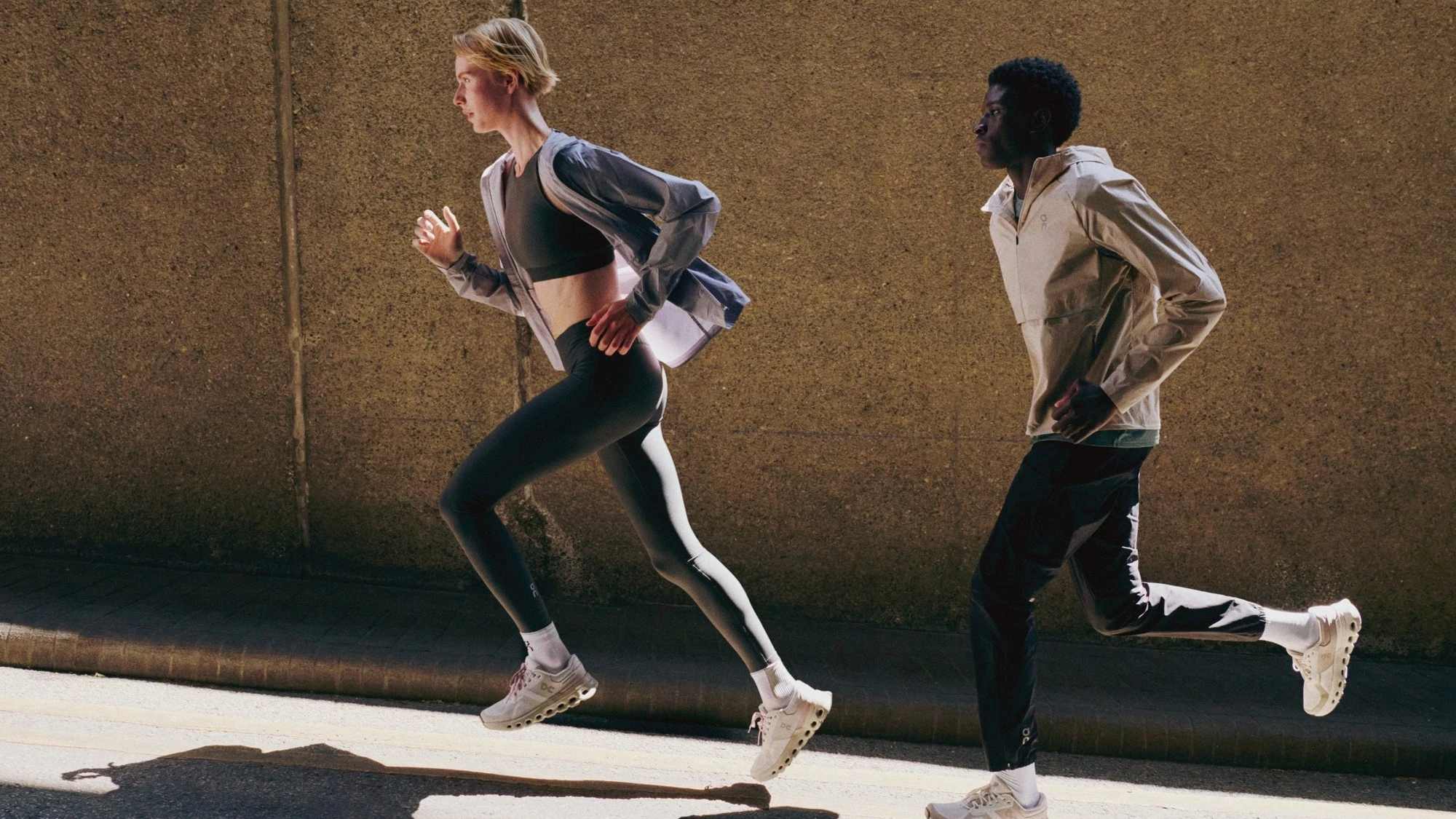 Two runners running up an inclined paved road.