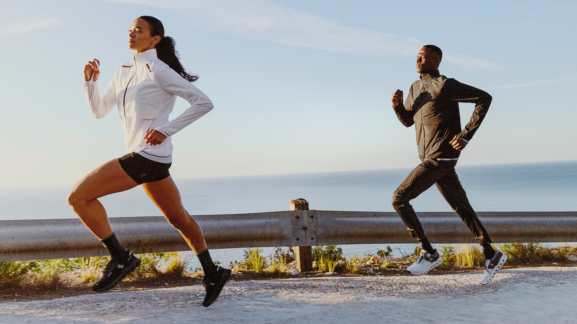 Woman and man running outdoors in athletic clothing and running shoes.