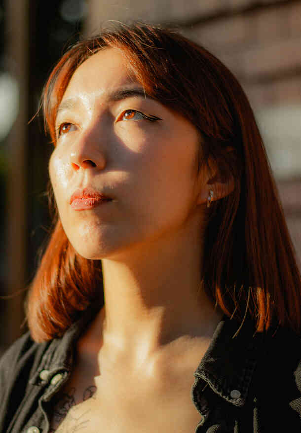 Woman in sunlight looking thoughtful.