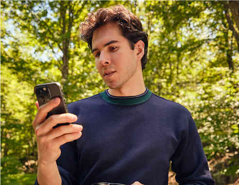 Man using phone outdoors in nature.