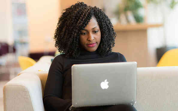 Woman using a laptop for online therapy at home.