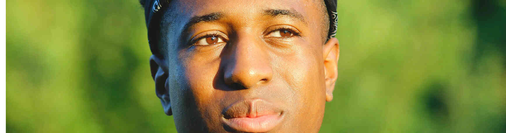 Man outdoors looking calm and reflective in sunlight.