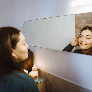 Woman looking at herself in mirror smiling.