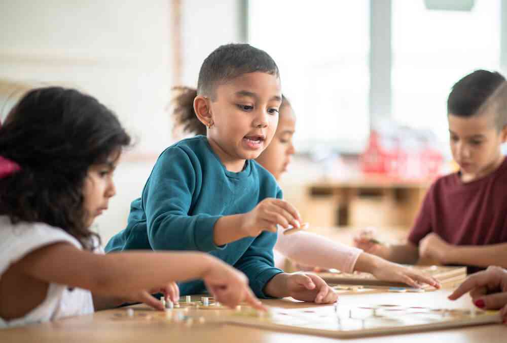 Children playing board game together in classroom.