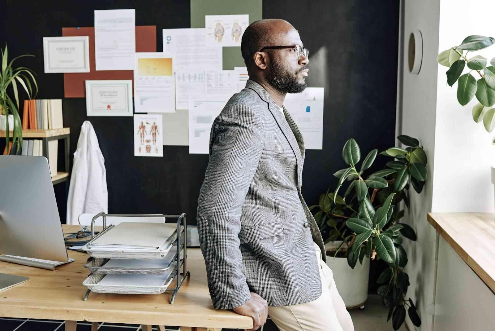 Man standing by window thinking in an office.