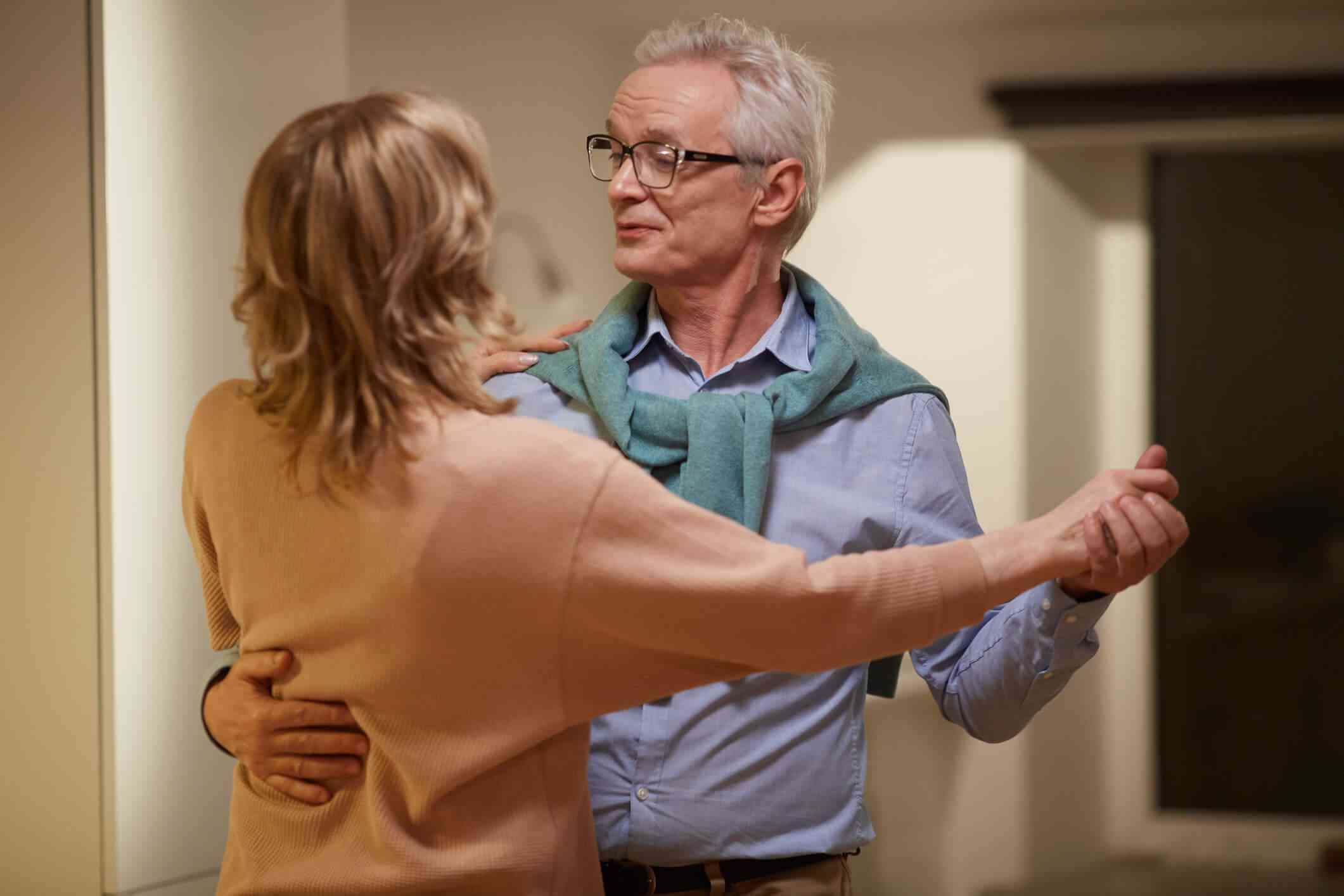 Older couple dancing together at home.