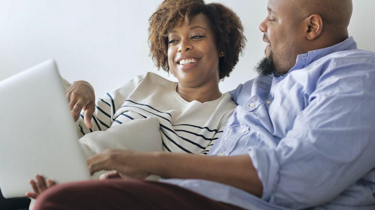 Couple relaxing on couch, smiling and talking.