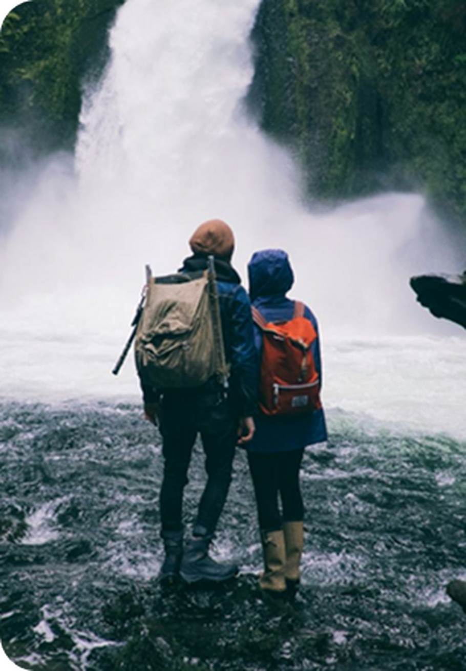 Couple standing together facing a large waterfall.