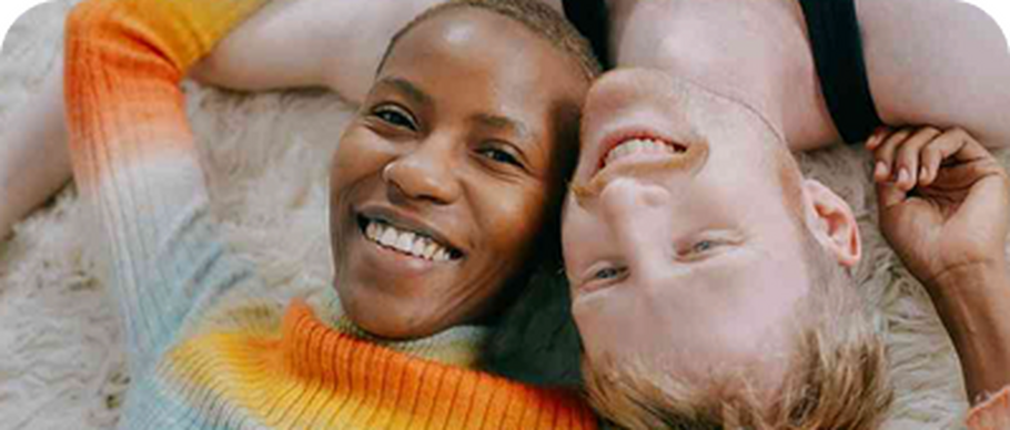 Couple lying together on the ground smiling at the camera.