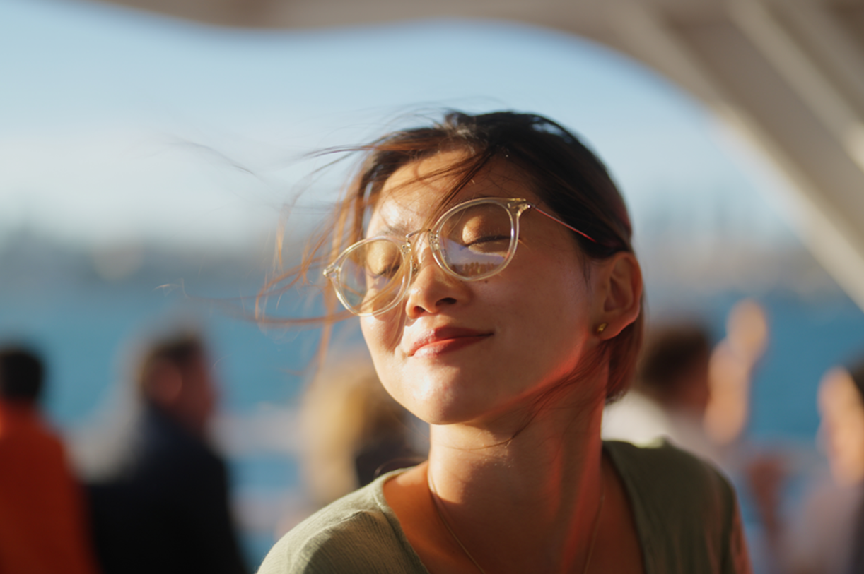 Woman with glasses smiling outdoors in golden-hour light
