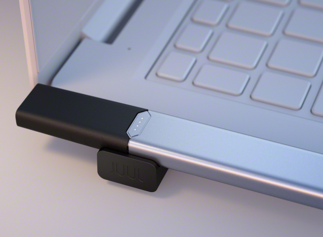 JUUL2 charging next to laptop keyboard.