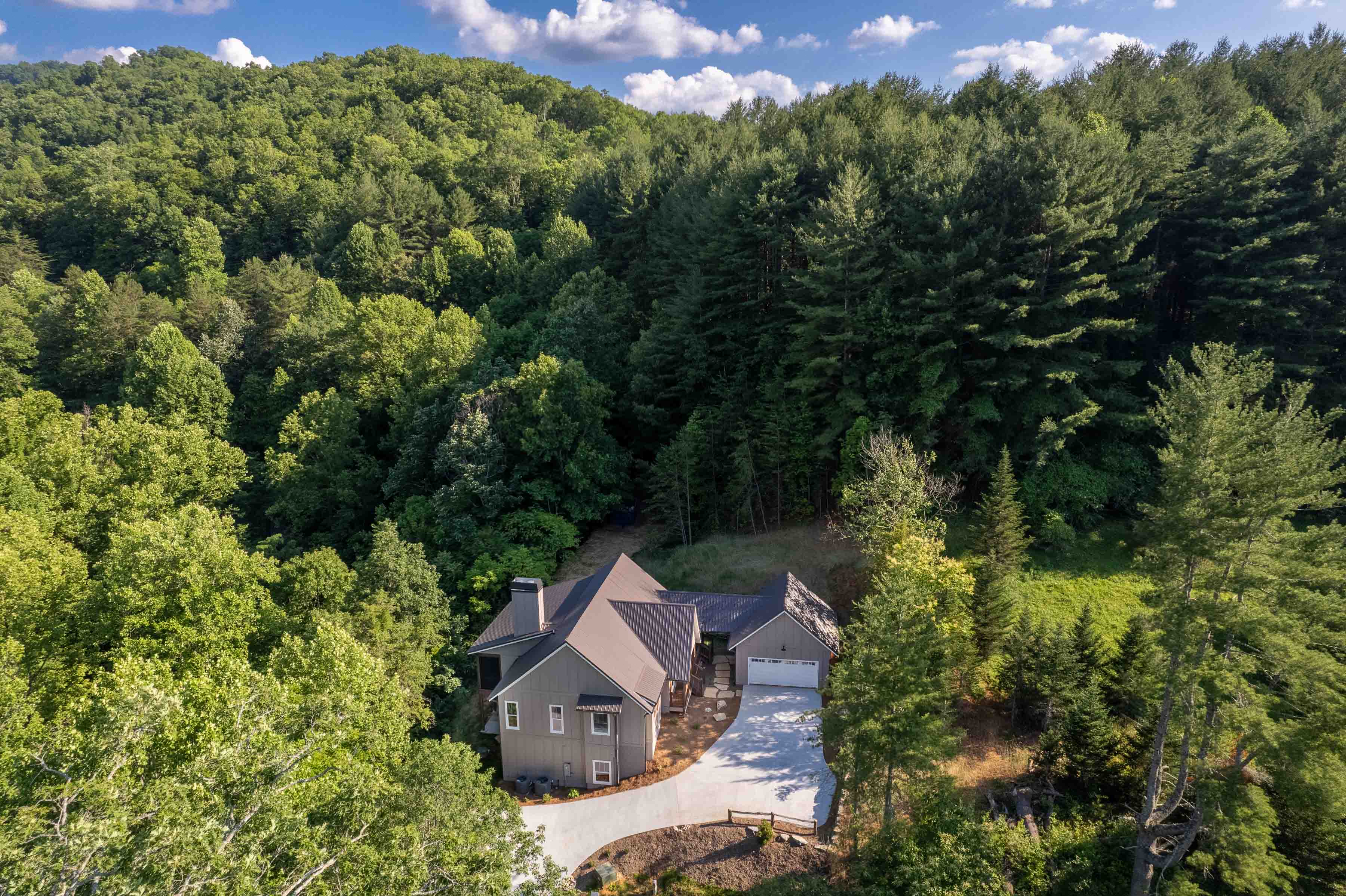 Sundrops home exterior aerial secluded in trees.