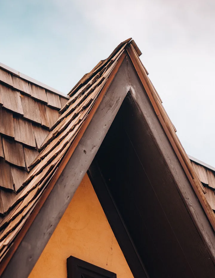 Close-up of a residential roof with layered wooden shingles and a steep gable