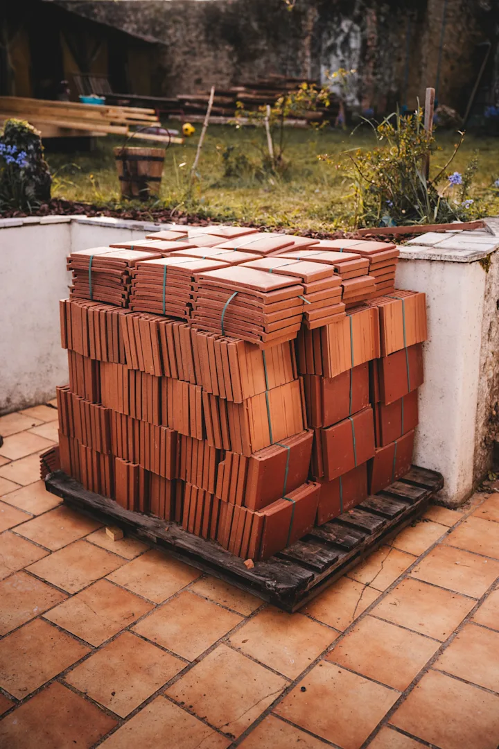 Unbranded pallet of stacked roof tiles staged outdoors before construction