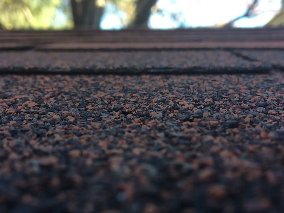 Close view of brown and gray mineral granules on layered asphalt roof shingles