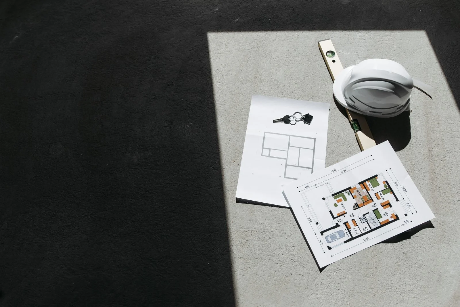 Construction plans, a hard hat, and a level arranged for contractor vendor onboarding