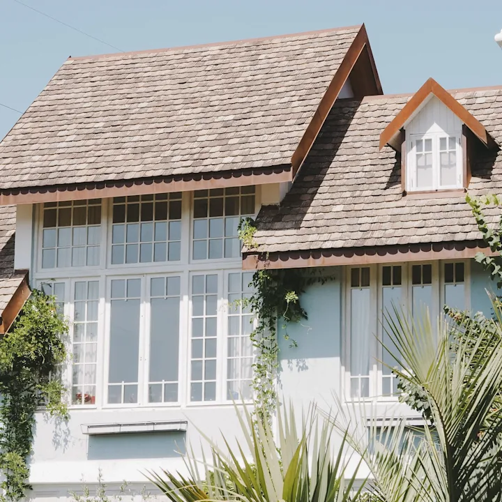 Residential home with a shingled roof, dormer window, and white exterior