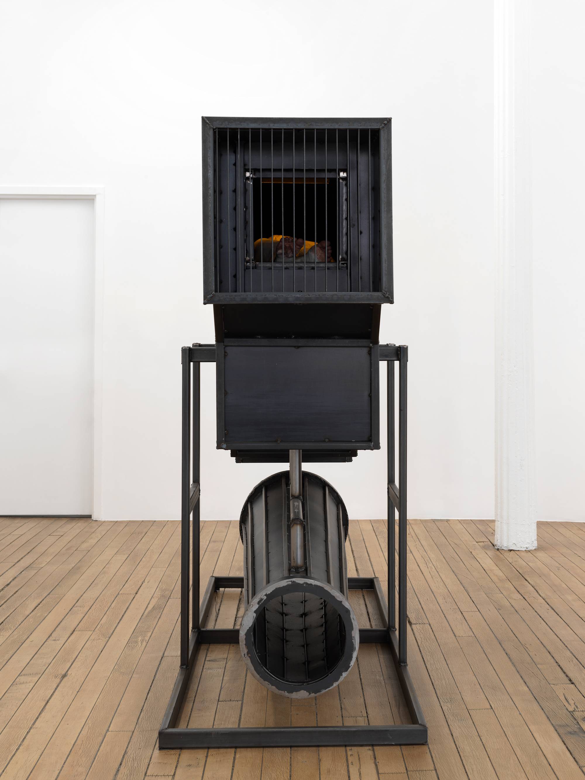 In a gallery space, a large steel sculpture resembling an abstract furnace.