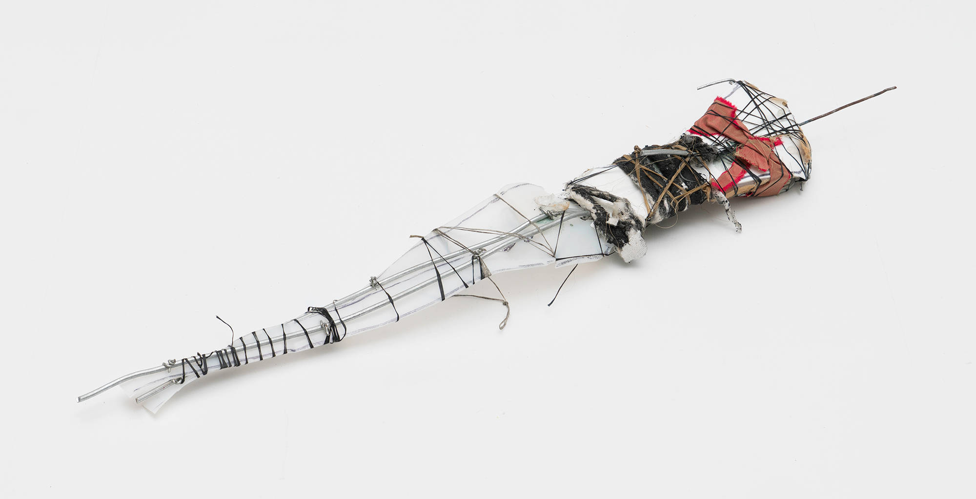 A small abstract sculpture resting on a white table constructed primarily out of wire and string.