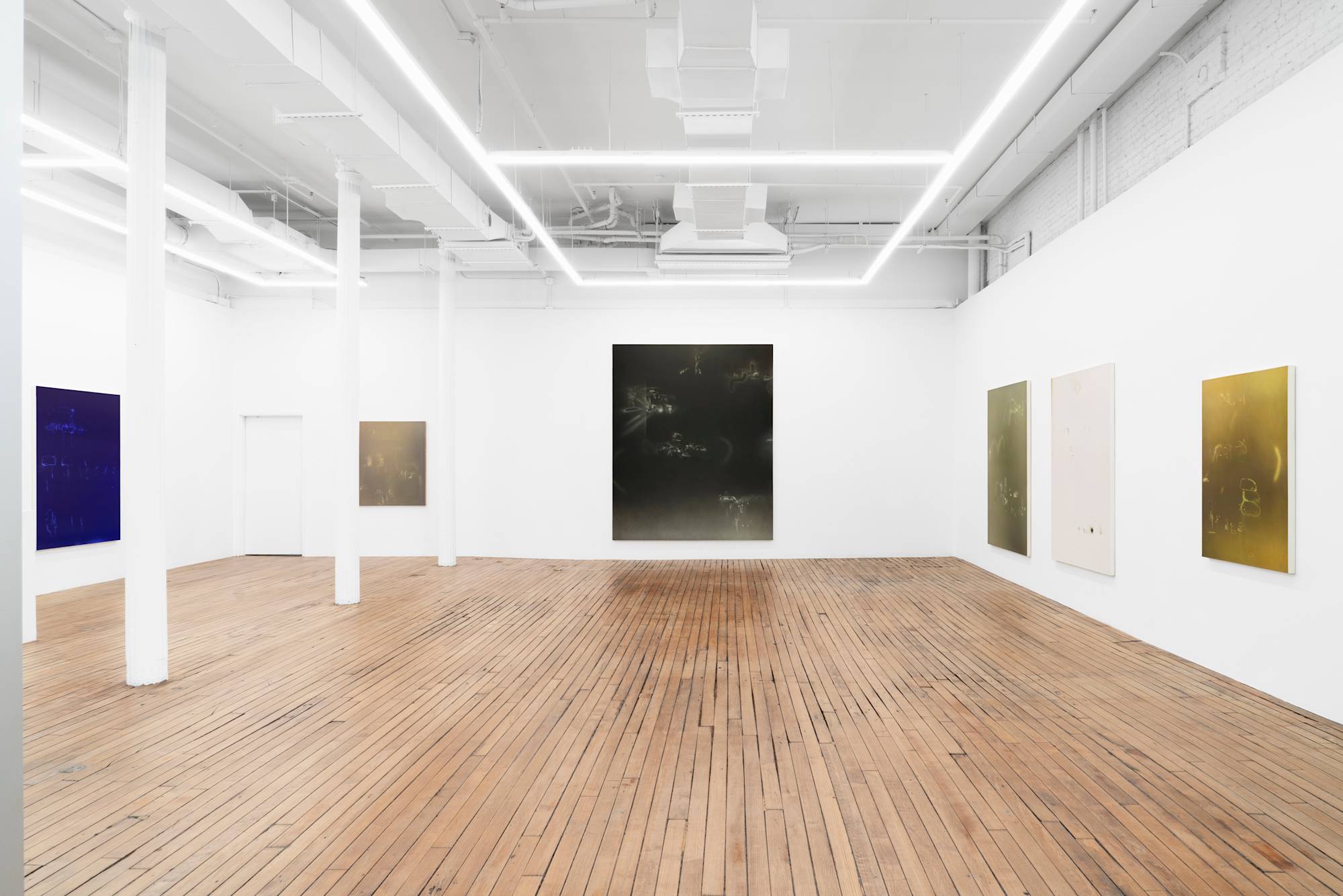 In a large open gallery space, there are six vertical abstract paintings containing an array of brushed marks on solid grounds of color.