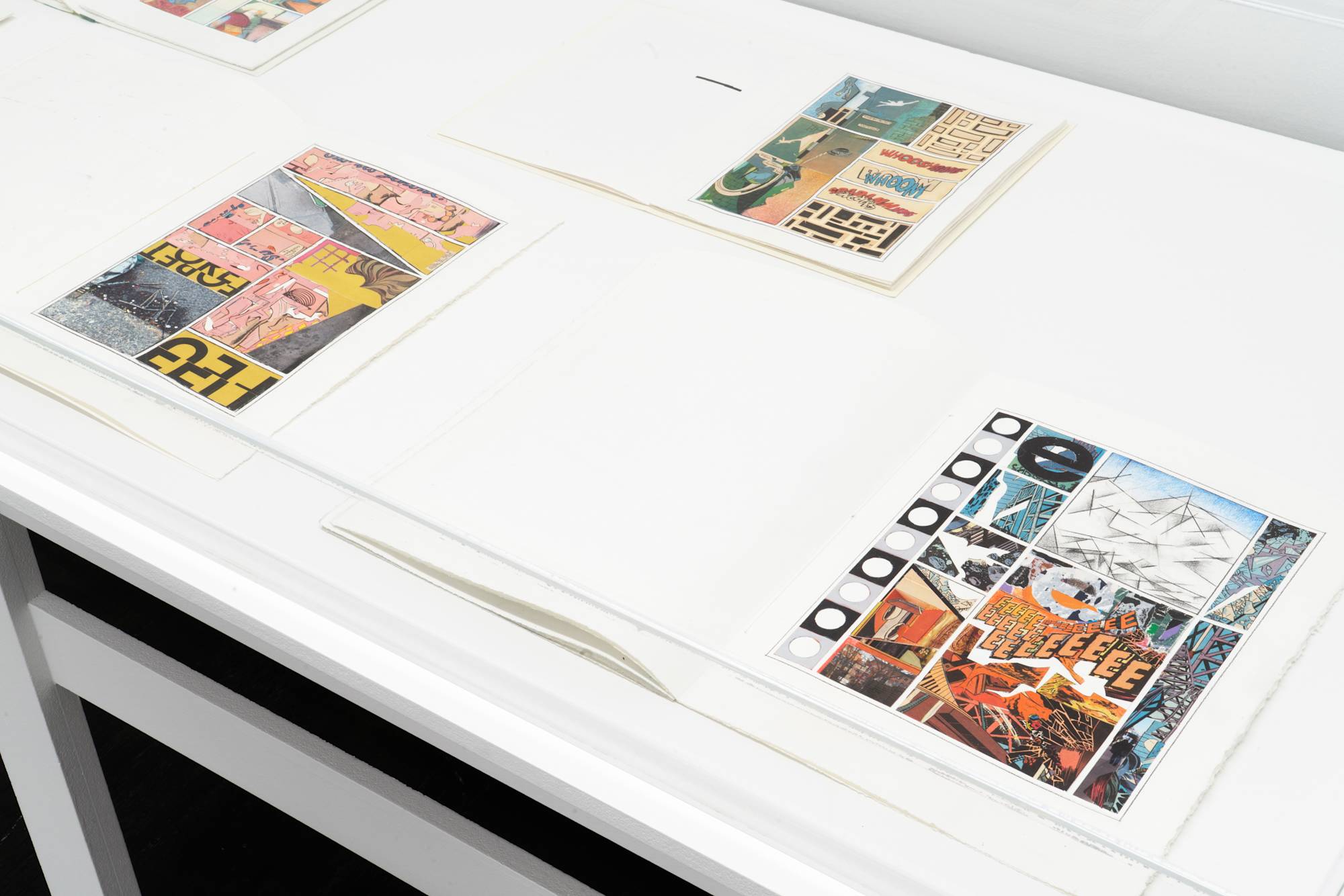 Placed on top of a vitrine are a series of artists books spread open revealing colored pencil drawings and comic book graphics.
