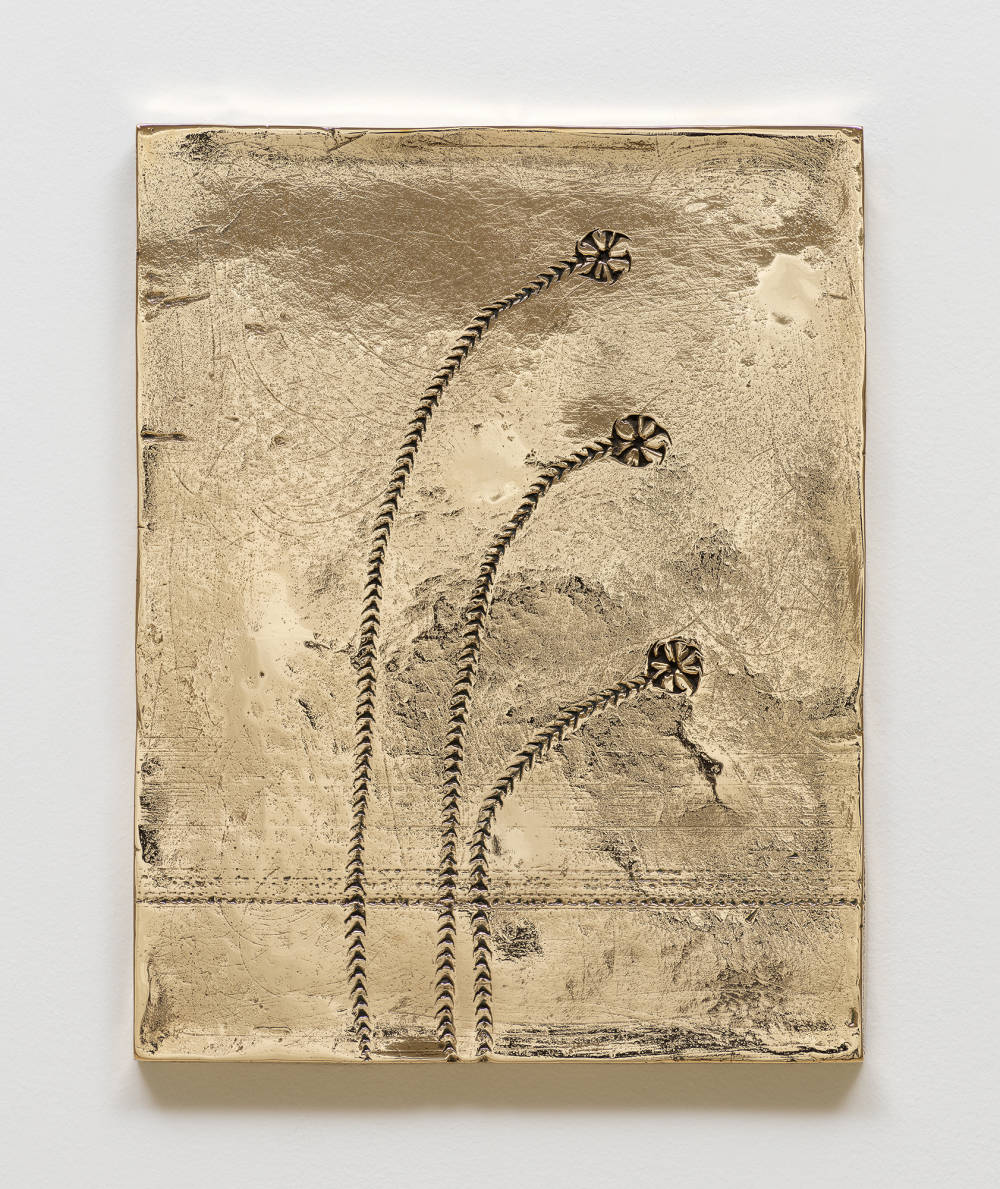 Image of a small cast bronze painting by Davina Semo depicting three flower-like indentations in the surface of the painting.