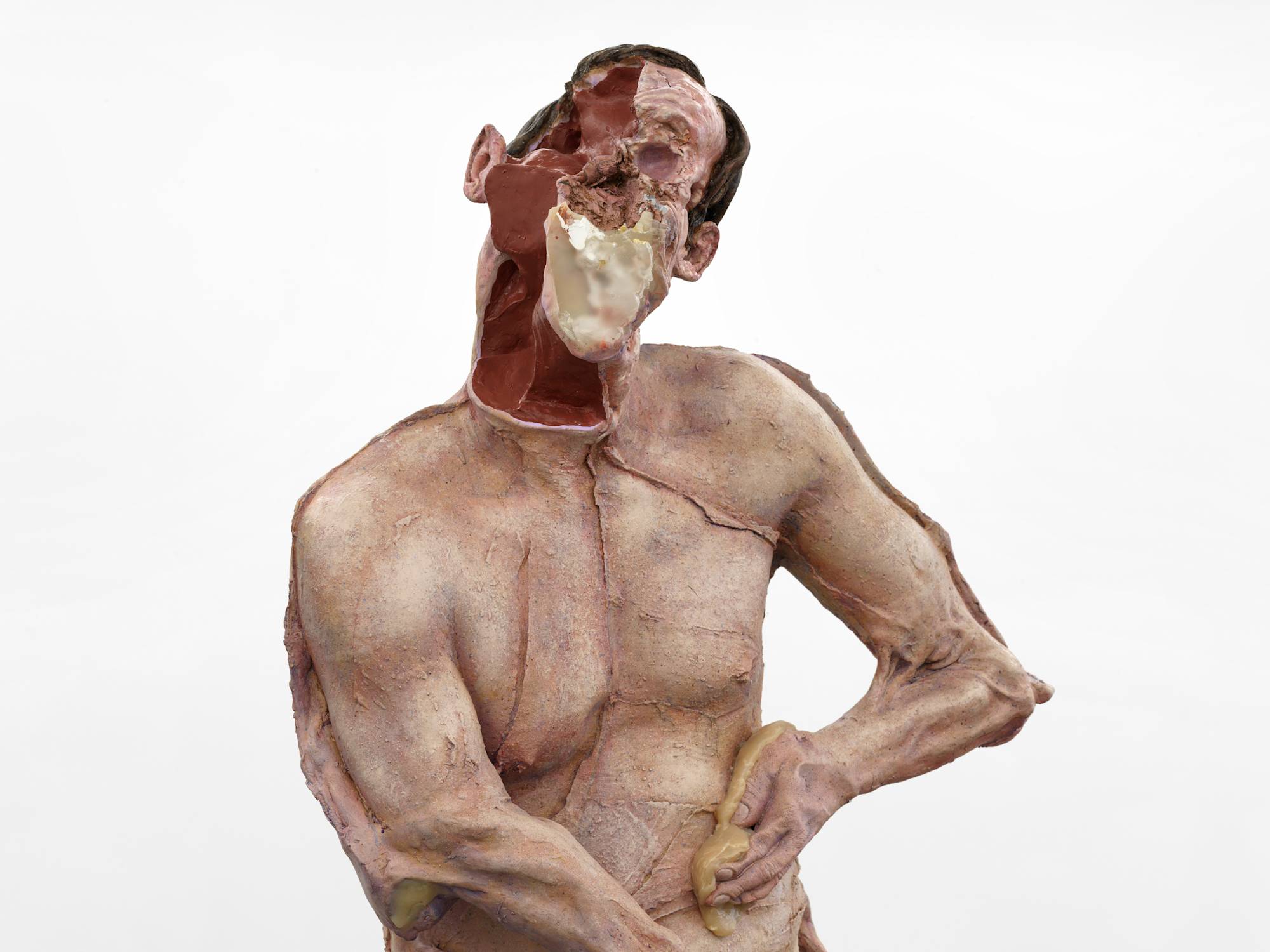 A close up view of a large sculpture depicting an abstracted naked body of a man with his head disfigured.