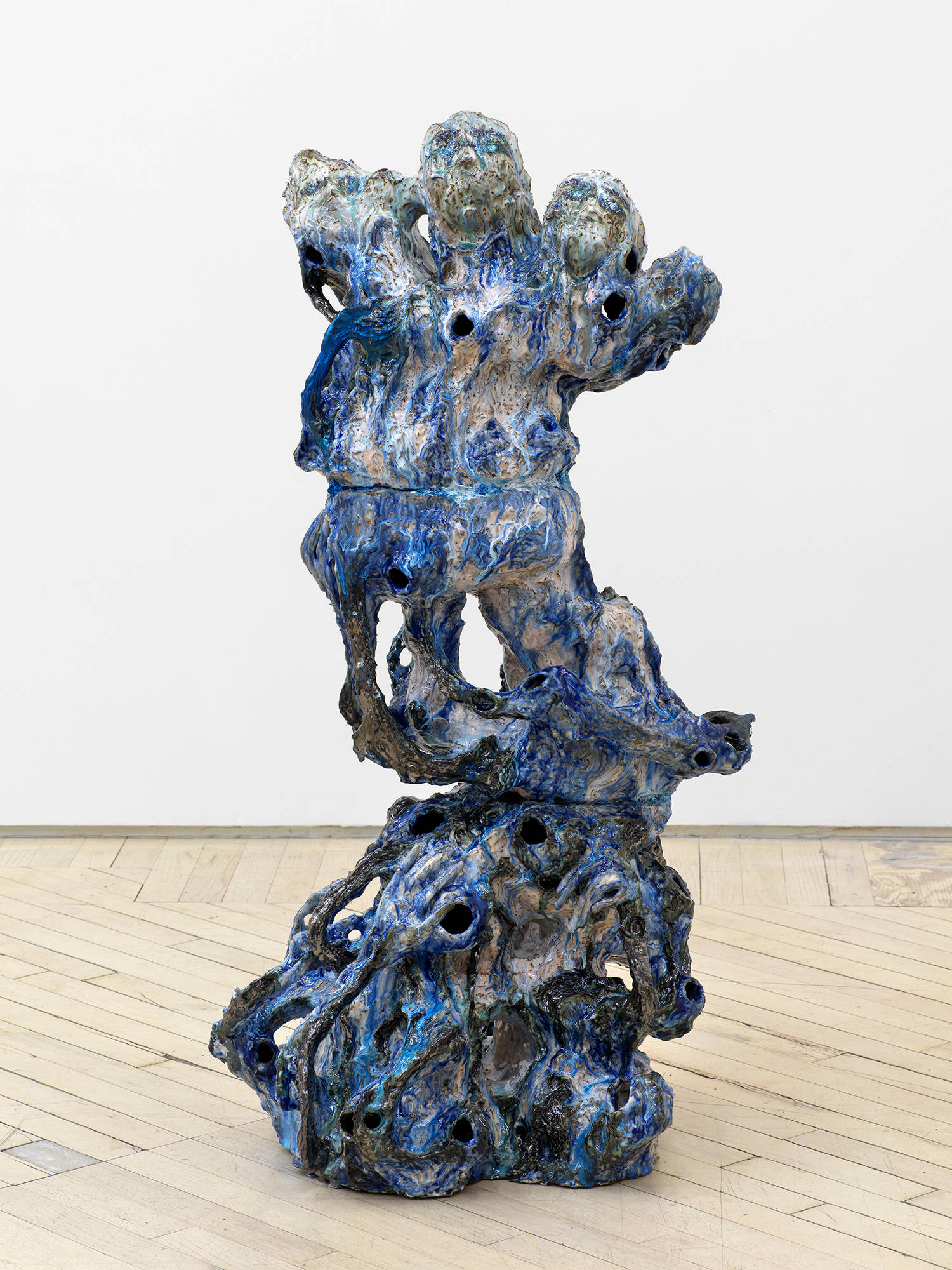 A freestanding, abstract ceramic sculpture resembling a figure merging from a landscape.