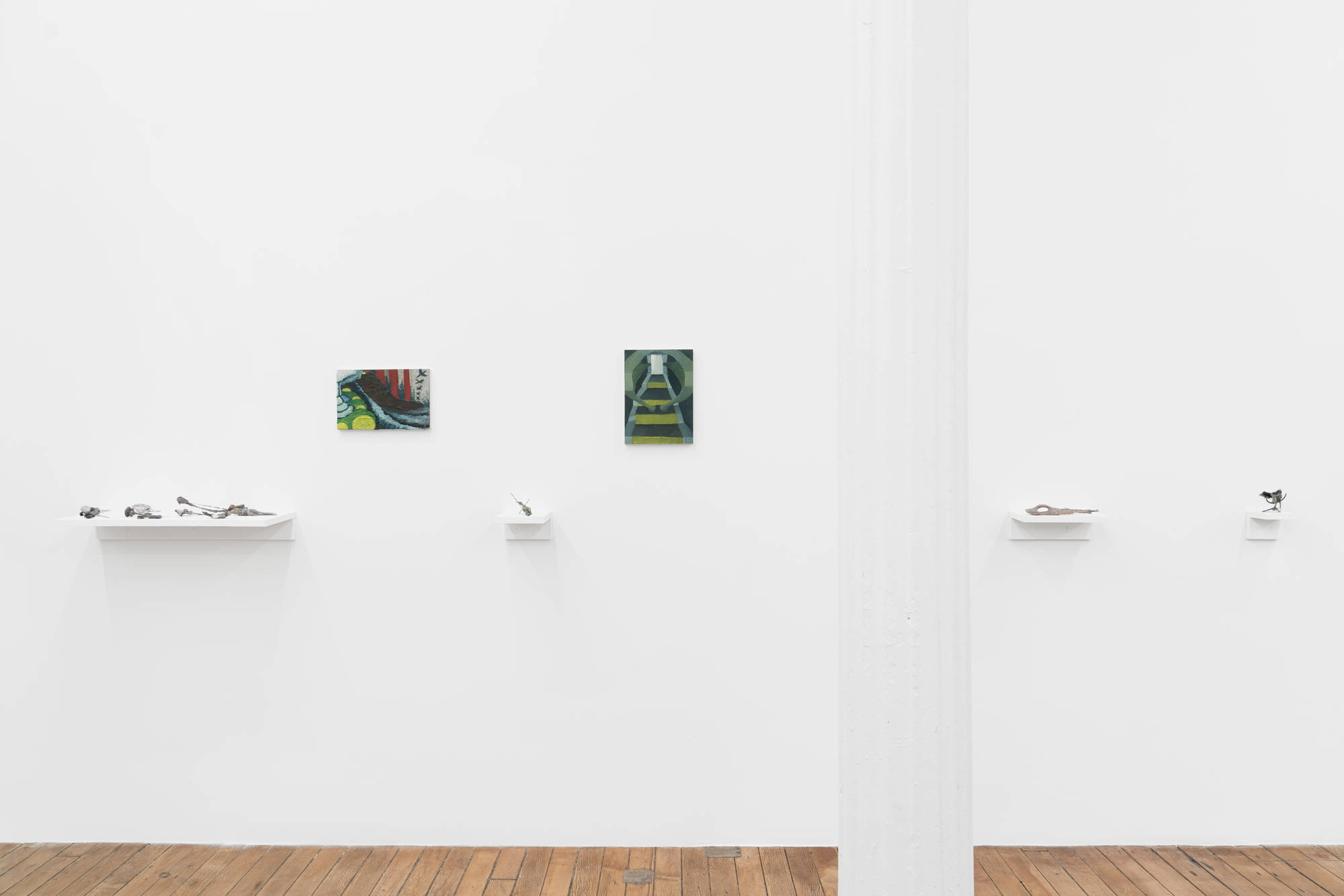 2 abstract paintings and 4 sculptures by Matt Hoyt hang on the wall in a gallery above a wood floor divided by a white column.