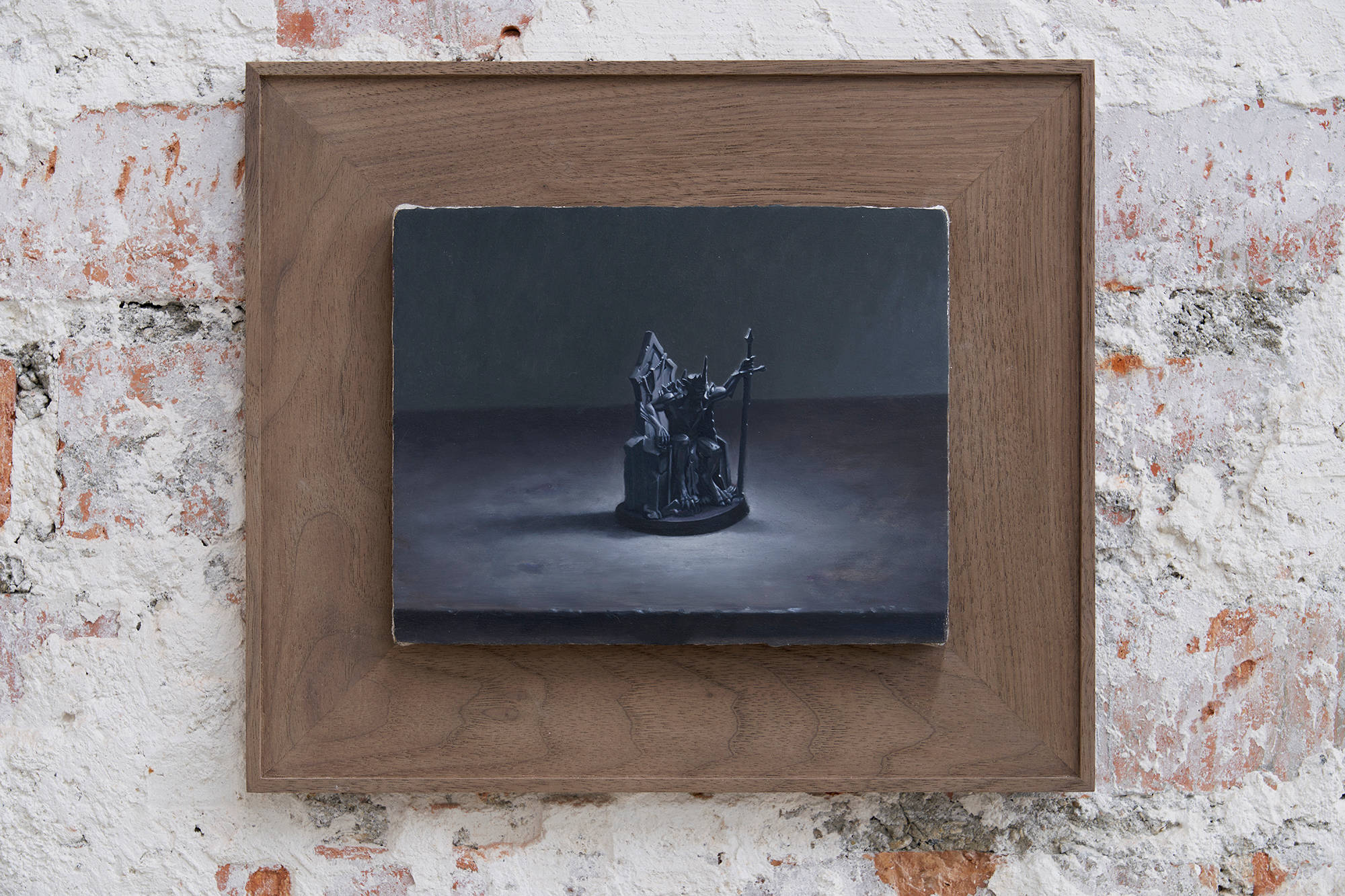 Installation view of Ian Miyamura paintings at the Paris Internationale fair, this painting showing a knight like figure seated in a dark spot lit room. The painting is framed in walnut.