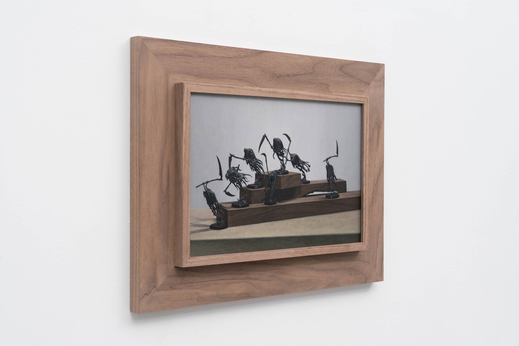 3/4 view of Ian Miyamura painting depicting seven unpainted Warhammer figures against a light grey background arranged on 3 tiers of wood blocks.