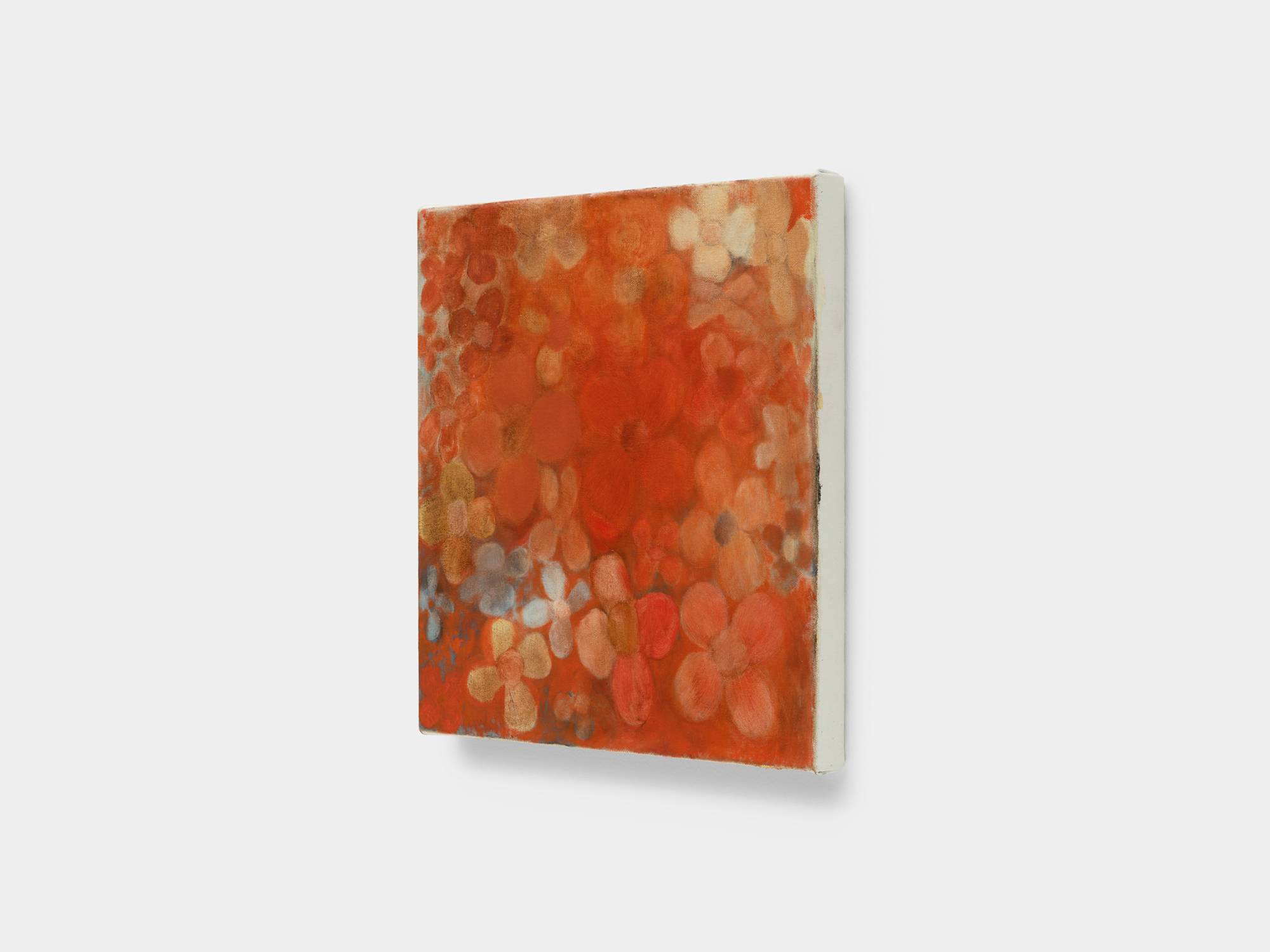 A side angle view of a small abstract painting of flowers in red, orange, and yellow hues.
