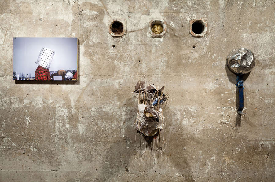 Installation view of artworks hung on a weathered concrete wall.
