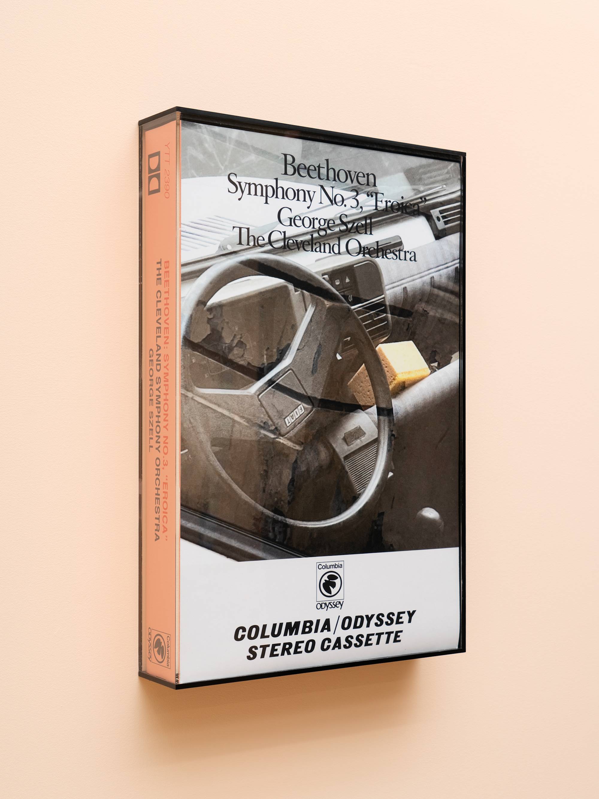 Oversized audio cassette case featuring an image of a car interior with a yellow sponge.