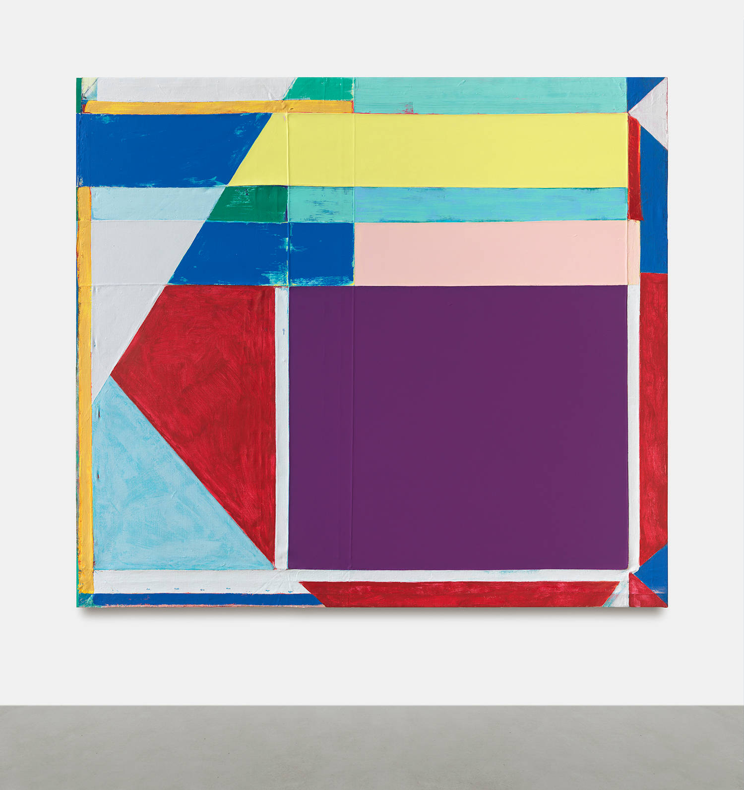 A large abstract painting on a white wall with gray floor below. The painting is a combination of discreet abstract shapes painted in bold colors. The outstanding colors are a hue of purple, red, blue, yellow and white. The paint is thick and brushy and the canvas is rough with creases.