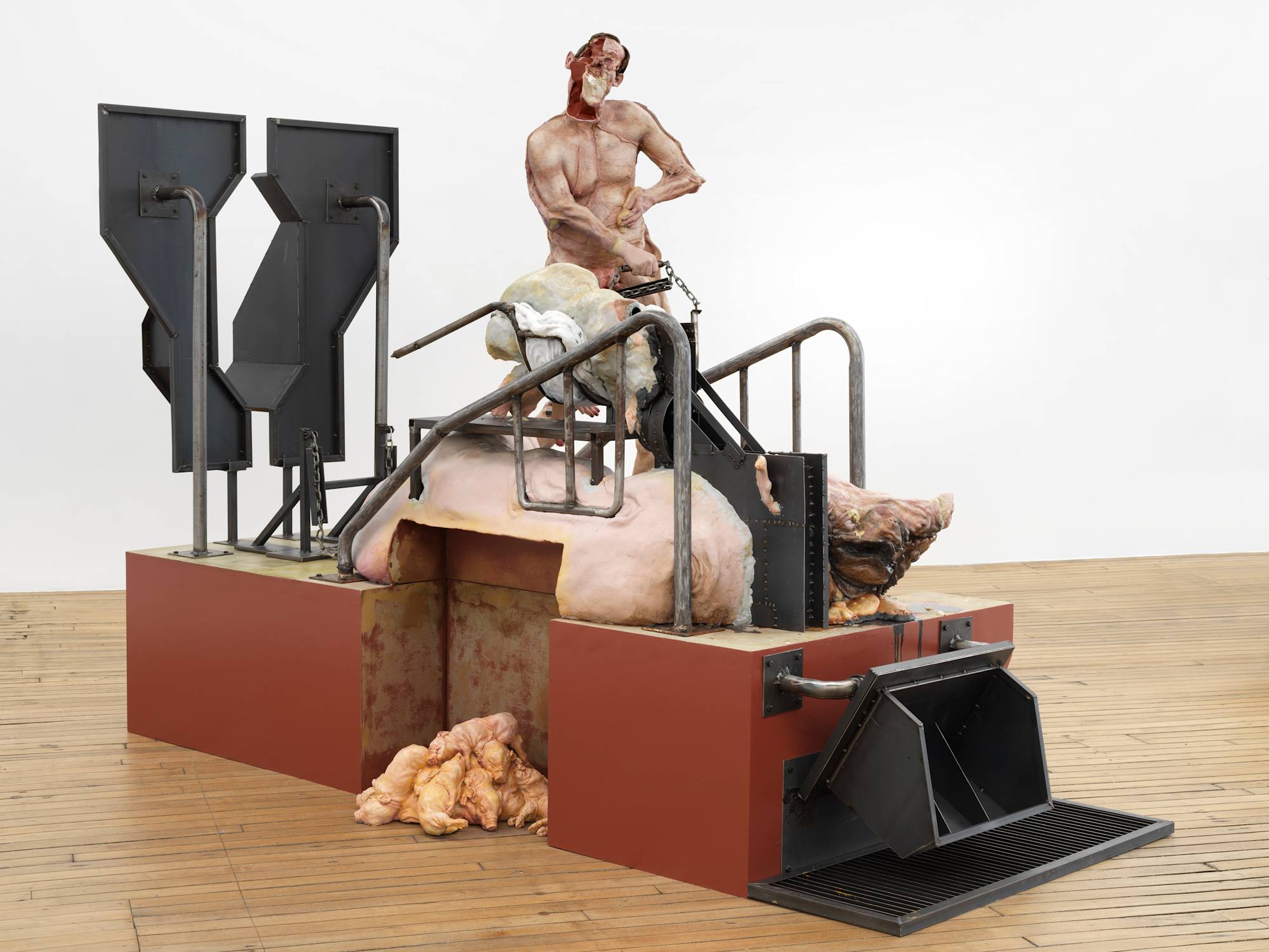 A monumental sculpture made primarily of steel and wood. Atop the base of the sculpture is an abstracted human form and a large pig.