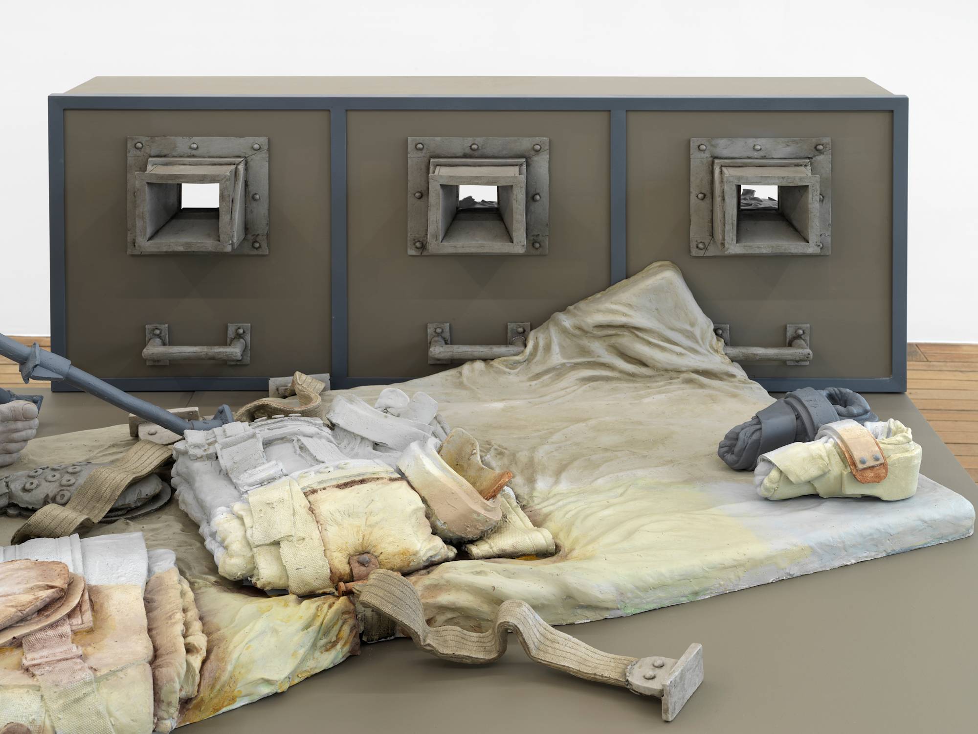 Close up image of a sculpture depicting abstracted human forms and structures that resemble cages.